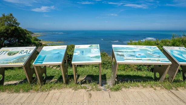 A coastal viewpoint with informational signs and a wooden deck.