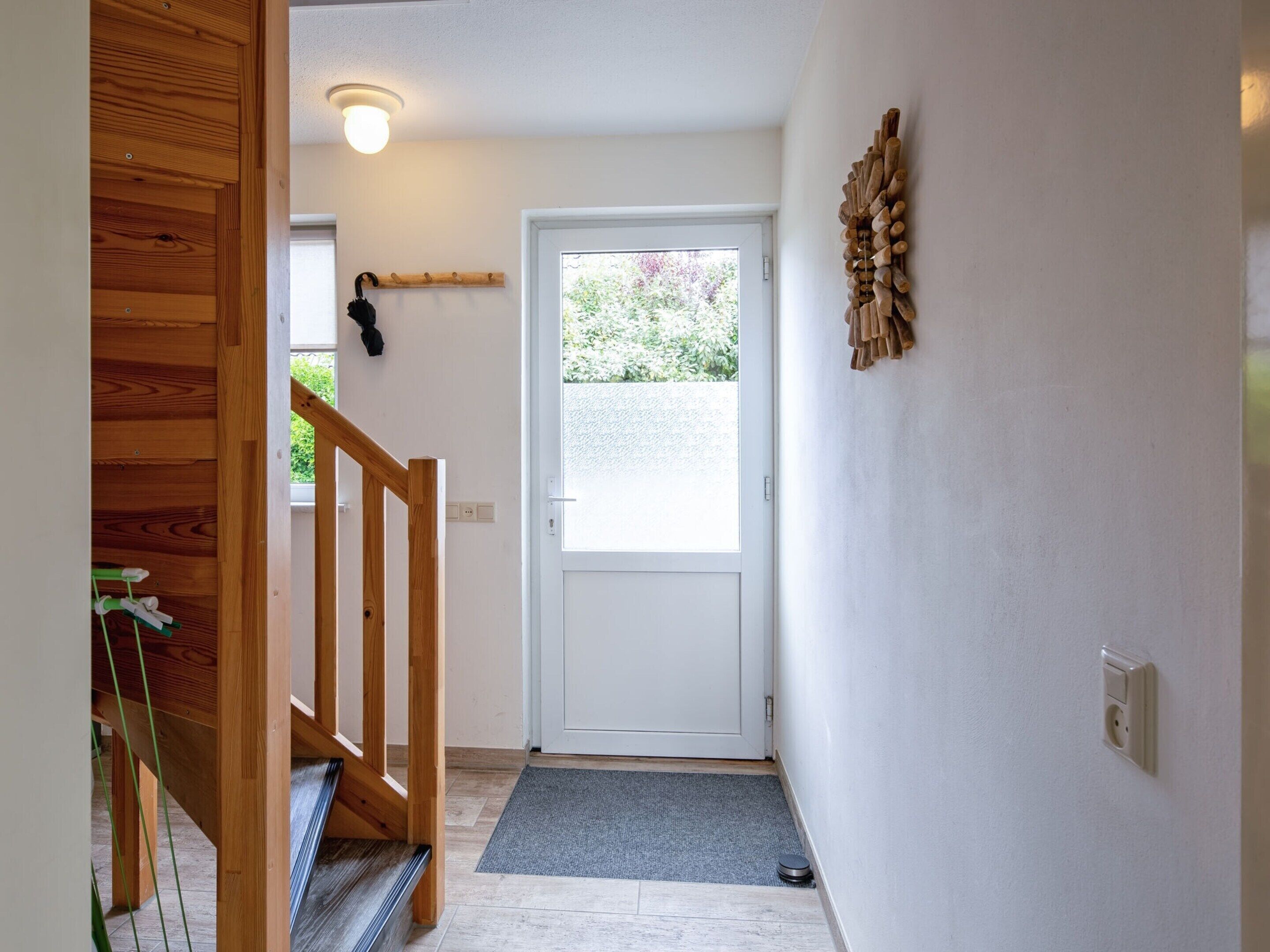 A hallway with a wooden staircase, a white door, and a small window.