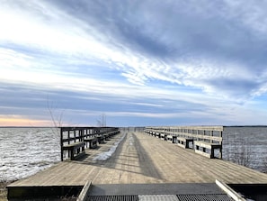 Une jetée en bois qui s’avance dans une étendue d’eau, avec des bancs disposés le long de sa longueur.