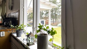Una cocina con ventana que da a un jardín, una cafetera y una planta en maceta en el alféizar.