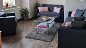 A modern living room with a sofa, a glass coffee table, and a lamp. - Holiday Apartment With a Terrace (Bremerhaven)