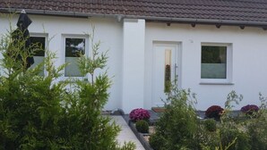 A white building with a brown roof, two windows, and a door. - Holiday Apartment With a Terrace (Bremerhaven)