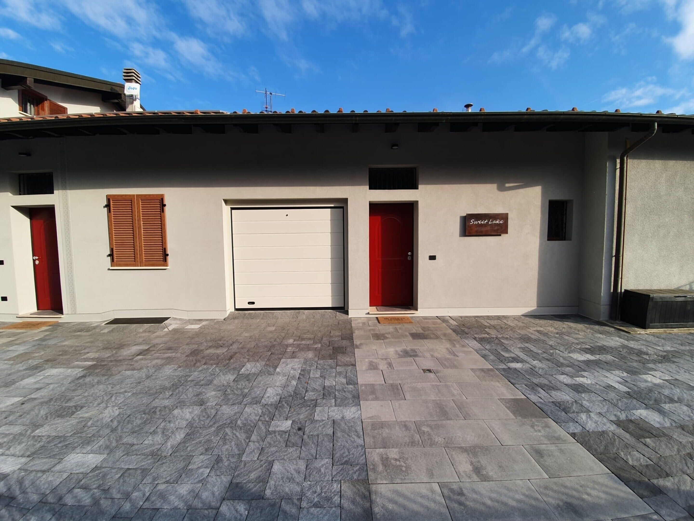 A building with a garage door, a red door, and a sign that reads "Sweet Lake".