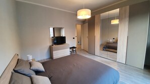 A modern hotel room with a large bed, a TV on a dresser, a mirror, and a walk-in closet. - Belvilla by OYO Sweet Lake D'orta (Omegna)