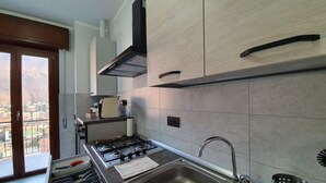 A modern kitchen with a gas stove, stainless steel sink, and wooden cabinets. - Belvilla by OYO Sweet Lake D'orta (Omegna)