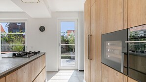 Una cocina moderna con armarios de madera, horno integrado y un refrigerador grande.
