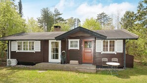 A log cabin with a front door, two windows with shutters, a small porch, and a table with chairs outside. - 5 Person Holiday Home in Vejby (Vejby)