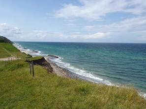 A coastal landscape with a grassy area, a paved path, and the ocean. - 5 Person Holiday Home in Vejby (Vejby)
