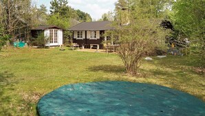 A backyard with a trampoline, a wooden house, and a garden. - 5 Person Holiday Home in Vejby (Vejby)
