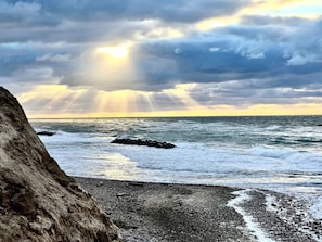 A rocky coastline with waves crashing against the shore and a cloudy sky.
