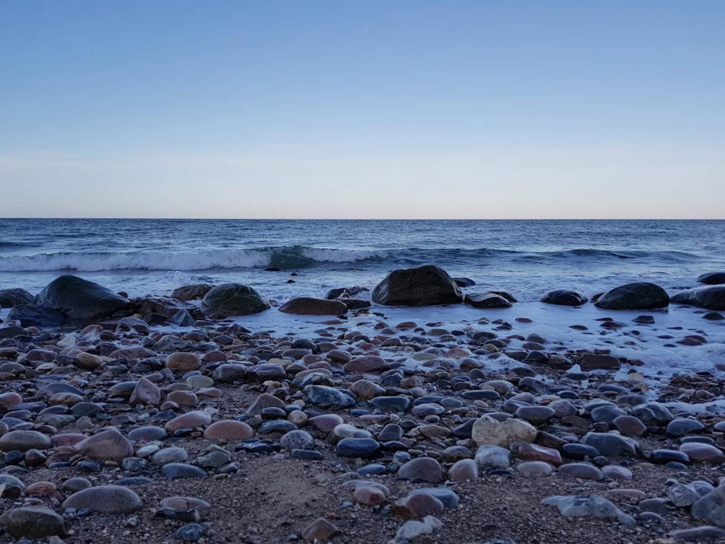 A rocky beach with large boulders and the ocean in the background.
