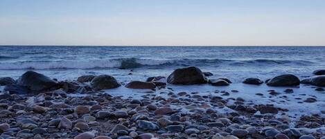 A rocky beach with large boulders and the ocean in the background.