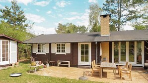 A wooden house with a patio, a table, and chairs. - 5 Person Holiday Home in Vejby (Vejby)