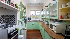 A compact kitchen with a gas stove, oven, microwave, and various kitchen utensils. - Albert Road Cottage: Comfy, vintage home near water & town  (East Bunbury)
