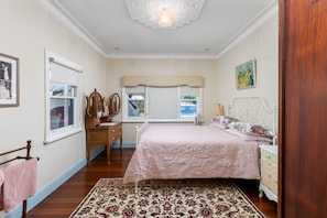 Une chambre à coucher avec un lit, une commode et une fenêtre donnant sur un beau paysage.