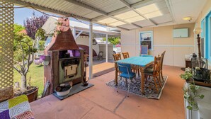 A covered patio with a table and chairs, a grill, and a potted tree. - Albert Road Cottage: Comfy, vintage home near water & town  (East Bunbury)