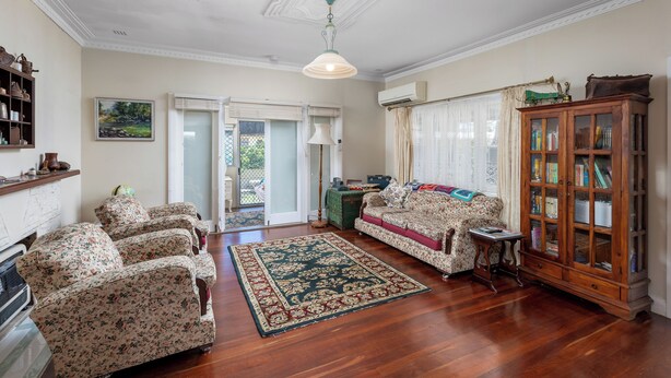 A spacious living room with floral-patterned armchairs, a wooden cabinet, and a large rug. - Albert Road Cottage: Comfy, vintage home near water & town  (East Bunbury)