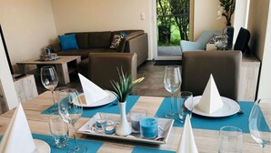 A dining area with a table set for two, featuring a blue tablecloth, white napkins, and a vase with a plant.