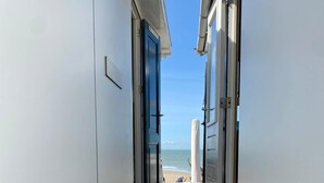 A corridor leading to a beach with a surfboard visible. - Holiday Home in Dishoek by the Beach (Koudekerke)