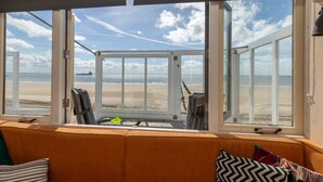 A room with a view of the beach, featuring a sofa and a window with a view of the ocean. - Holiday Home in Dishoek by the Beach (Koudekerke)