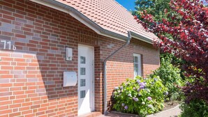 Une maison en briques avec un toit en tuiles, une porte blanche et une boîte aux lettres.