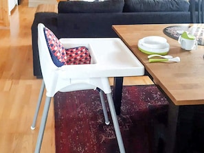 A dining area with a high chair, a table with a plate, a cup, and a spoon. - 7 Person Holiday Home in Oviken (Oviken)