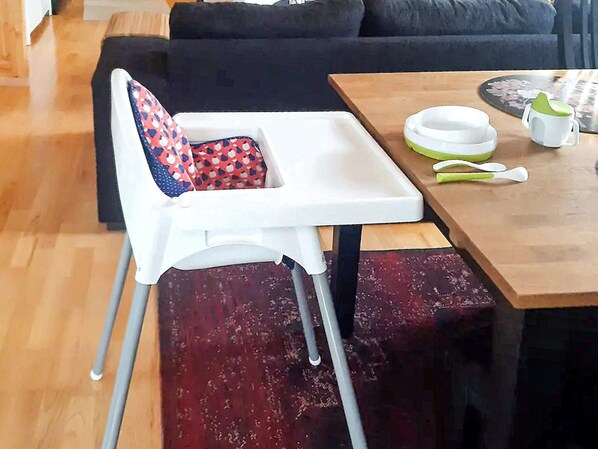 A dining area with a high chair, a table with a plate, a cup, and a spoon.