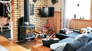A cozy living room with a wood-burning stove, a television, and a sofa.