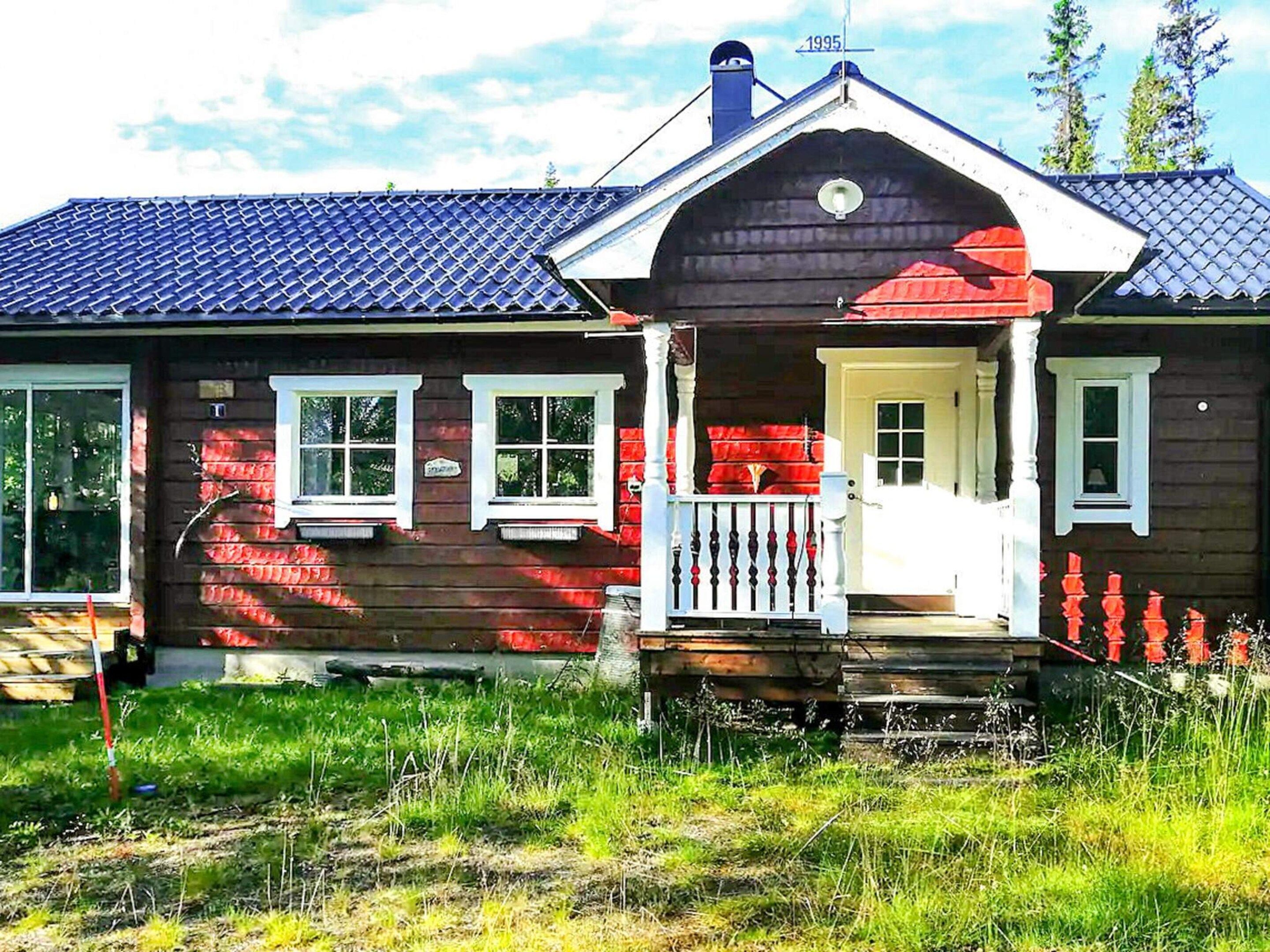 A wooden house with a porch, a chimney, and a small garden area.