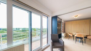 Un appartamento moderno con ampie finestre, un'area pranzo e vista sulla città.