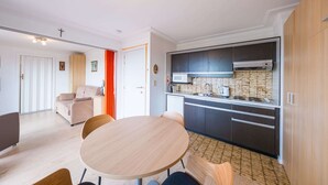 Una cucina moderna con mobili scuri, un forno a microonde e un piano cottura. C'è un'area pranzo con un tavolo rotondo e sedie.