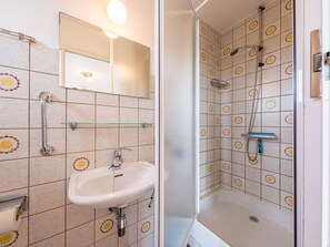 A bathroom with a sink, mirror, and shower. - Cozy Studio on the 5th Floor With Terrace (Middelkerke)