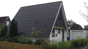 A house with a steeply pitched roof, a small front porch, and a white exterior. - Long Comfortable Holiday Residence (Cuxhaven)