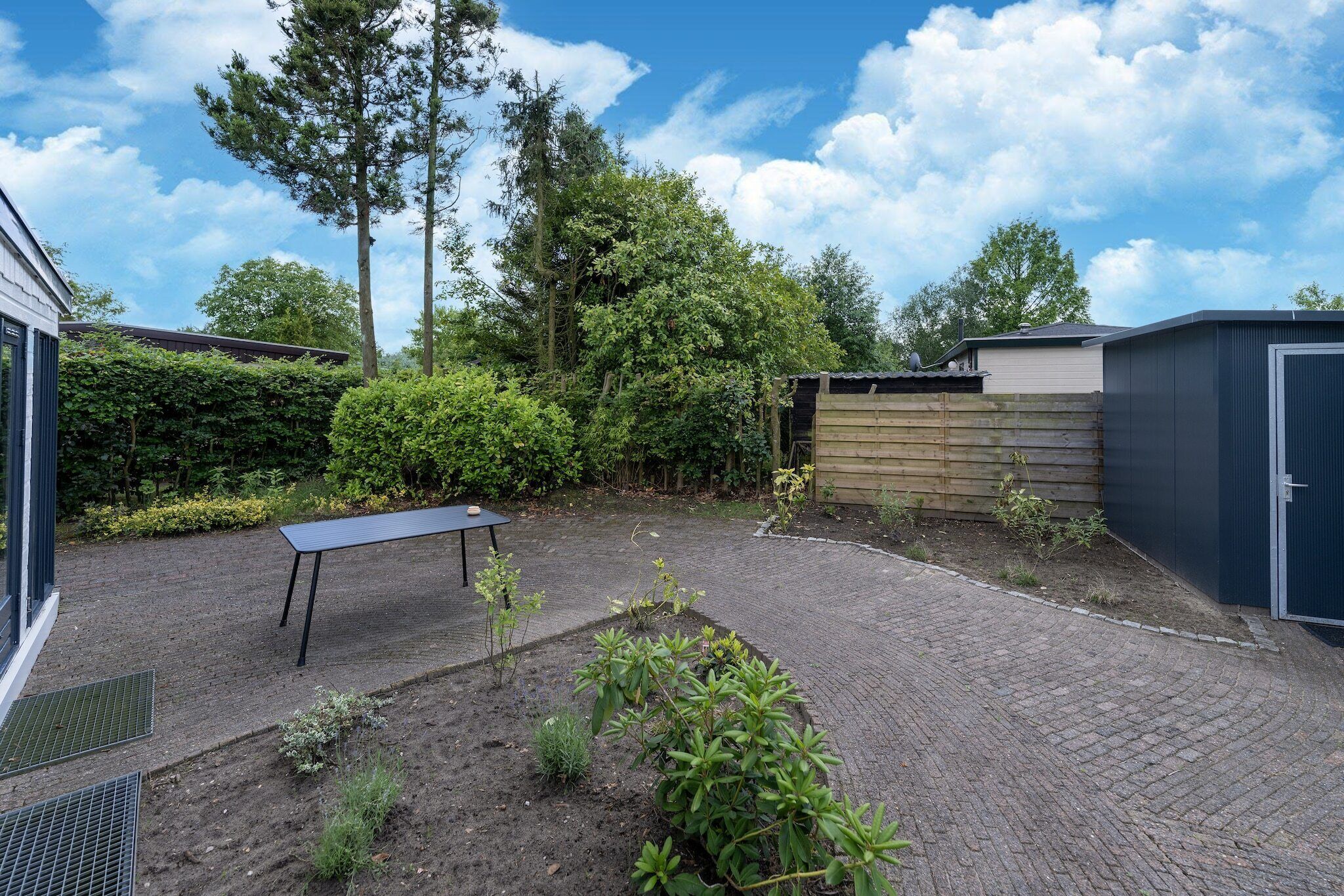 A backyard with a paved area, a table, and a shed.