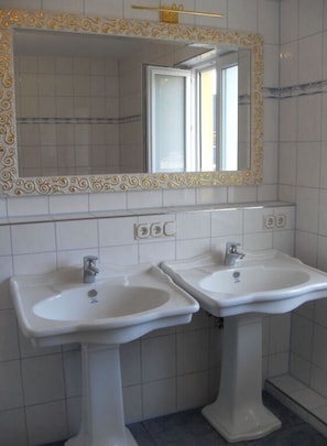 A bathroom with two pedestal sinks, a mirror with an ornate frame, and tiled walls. - Villa Lake Constance View (Stetten)