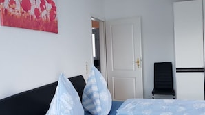 A hotel room with a bed, a black sofa, a painting on the wall, and a door leading to another room. - Villa Lake Constance View (Stetten)