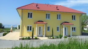 A yellow two-story building with a red-tiled roof, multiple windows, and a small front garden. - Villa Lake Constance View (Stetten)