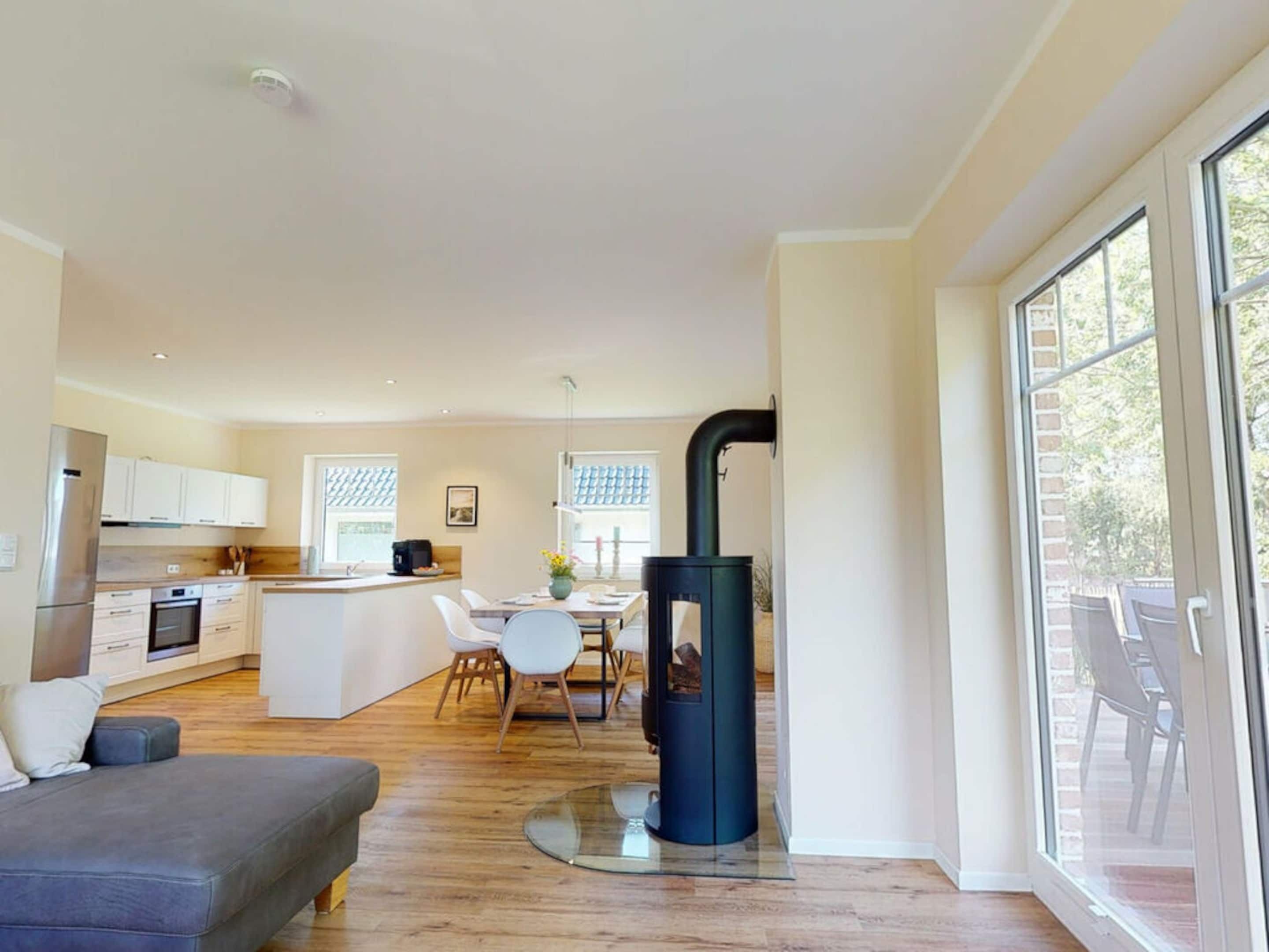 A modern kitchen with white cabinets, a dining area with a table and chairs, and a large window.