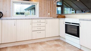 A kitchen with wooden cabinets, a window, and a stove. - 4 Star Holiday Home in Sydals (Sydals)