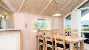 A wooden interior with a dining table and chairs, a hanging light fixture, and a window with a view of greenery. - 4 Star Holiday Home in Sydals (Sydals)