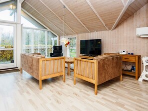 A modern living room with wooden furniture, a television, and a large window. - 4 Star Holiday Home in Sydals (Sydals)