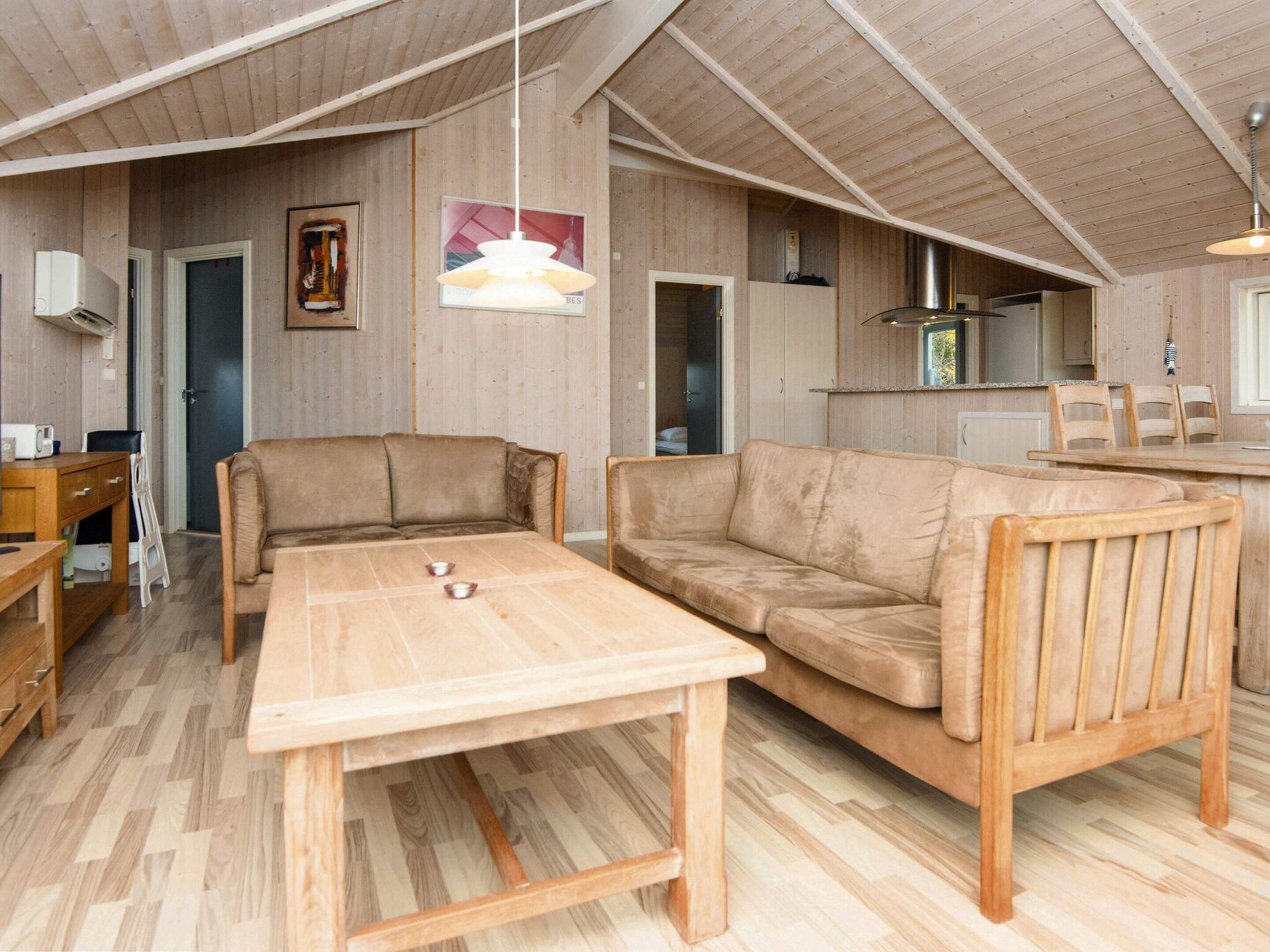 A cozy living area with a wooden table, two sofas, and a kitchen in the background.