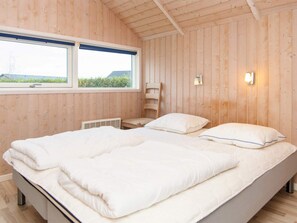 Un dormitorio con cama, ventana y una lámpara fijada a la pared.