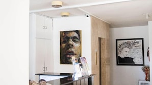Un área de recepción con un mostrador de mármol negro, un armario blanco y una obra de arte enmarcada en la pared.