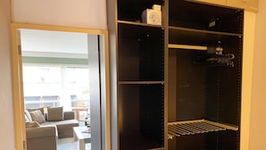 Een kamer met een grote, donkere garderobe, een grijze bank en een klein tafeltje met een lamp.