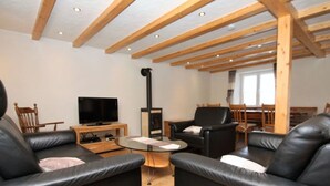 A modern living room with black leather sofas, a wooden TV stand, and a fireplace. - Eifel Farmhouse Comfortable Holiday Residence (Plütscheid)