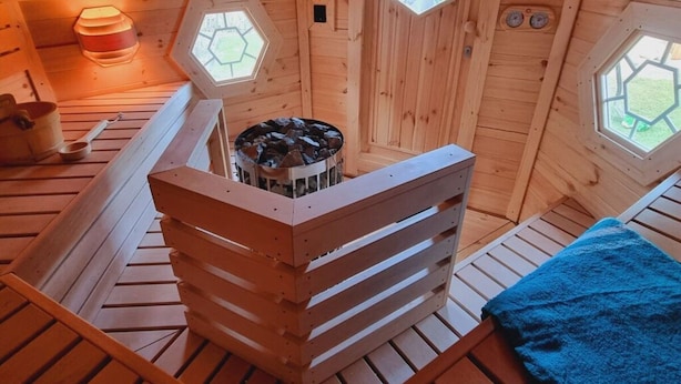 Un sauna de madera con ventanas hexagonales, un banco de madera y un hogar.