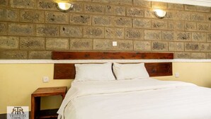 A bedroom with a brick-patterned headboard, two wall-mounted lights, and a wooden nightstand.