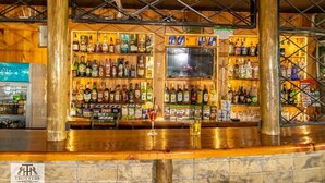 A bar area with shelves of liquor bottles, a TV screen, and a sign for Trotters Hotel.