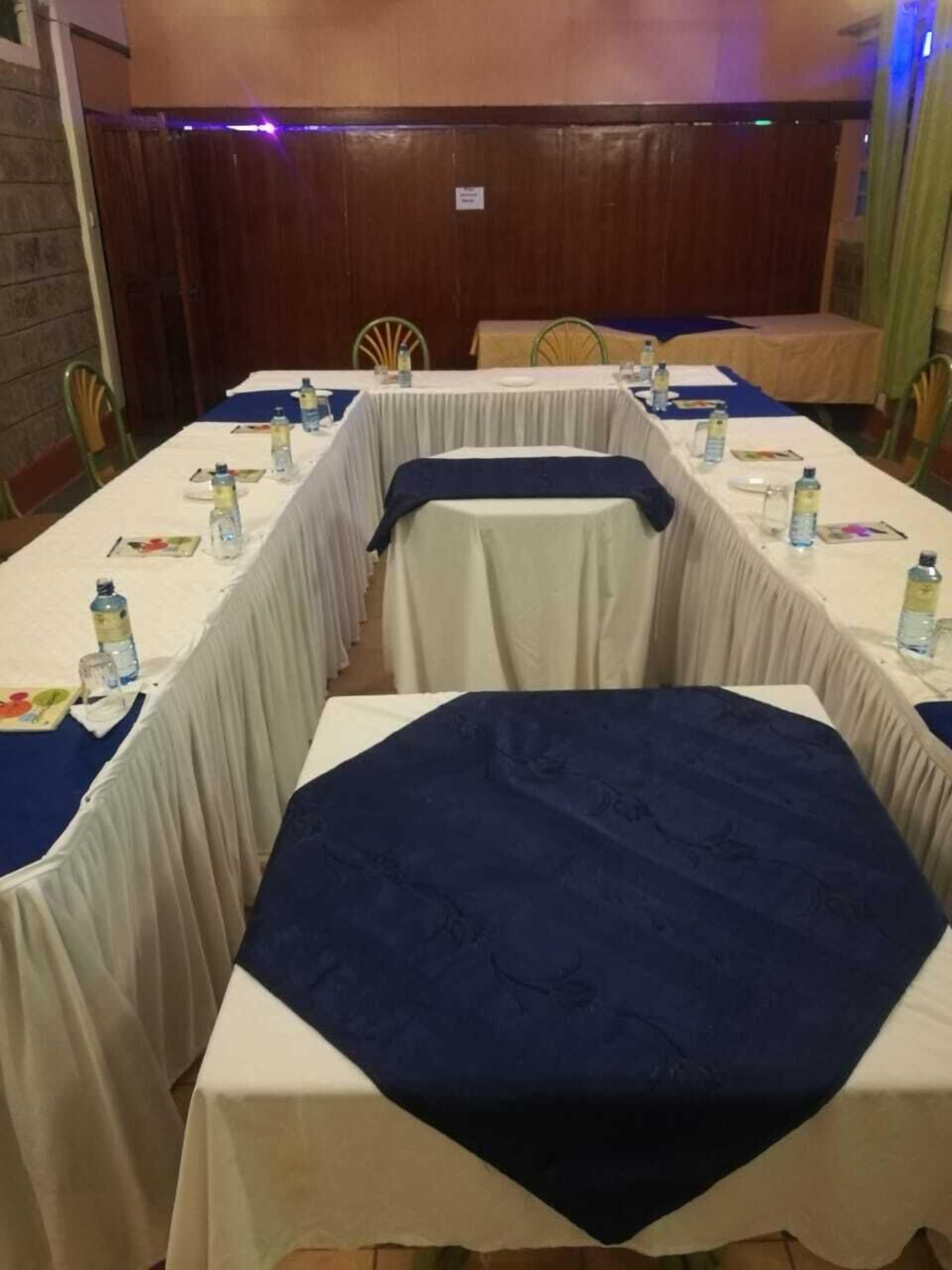 Un salón de conferencias con una larga mesa, sillas y botellas de agua.